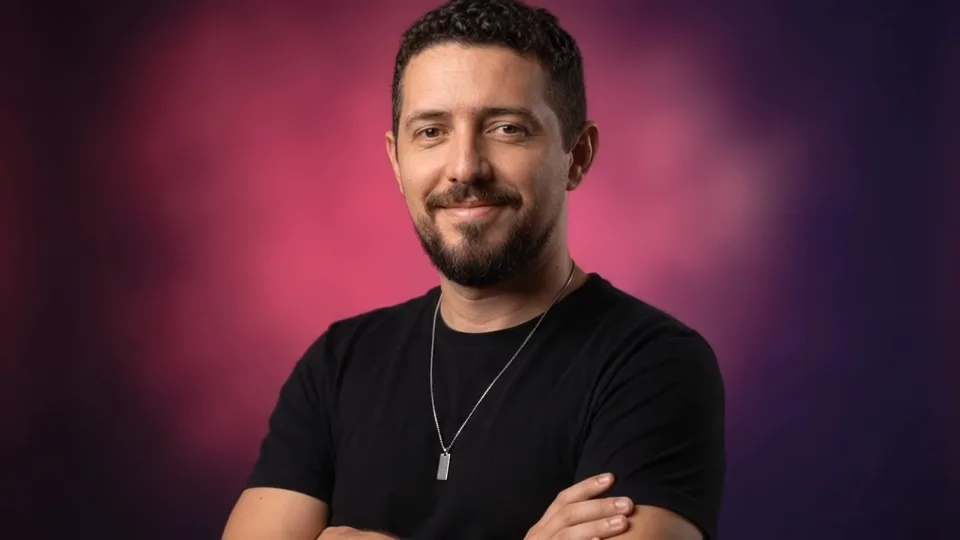 Michael, web designer, sorrindo de braços cruzados